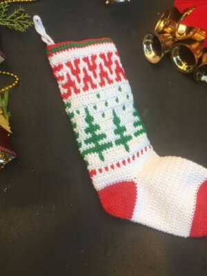 Red, white and green mosaic crochet Christmas stocking on a black background